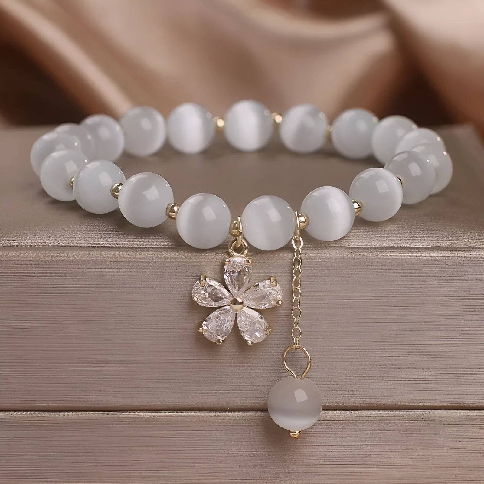 Women's white cat's eye stone bracelet with flower tassel and safety buckle pendant.
