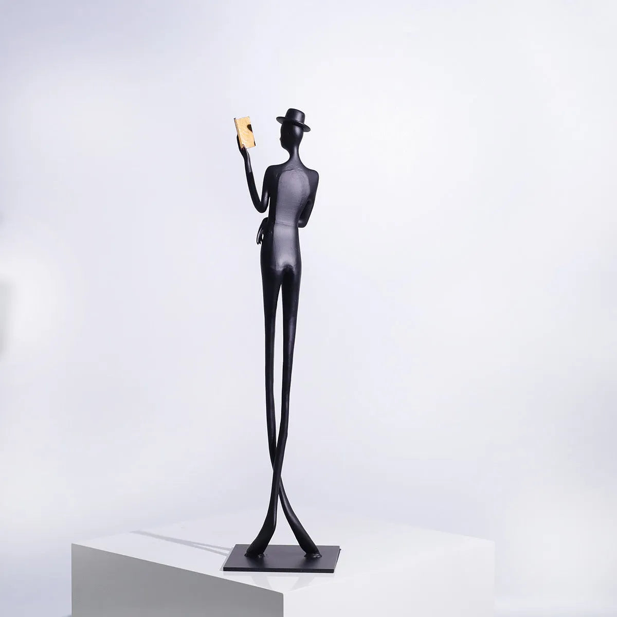 Black metal desktop sculpture of a woman reading, 51cm tall.