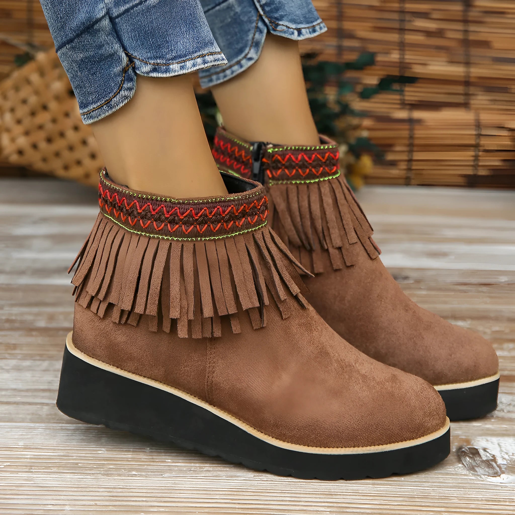 Women's suede ankle boot with wedge heel, side zipper, and tassel detail in dark brown.