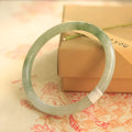 Green jade waxy geometric bracelet with Chinese styling on wrist