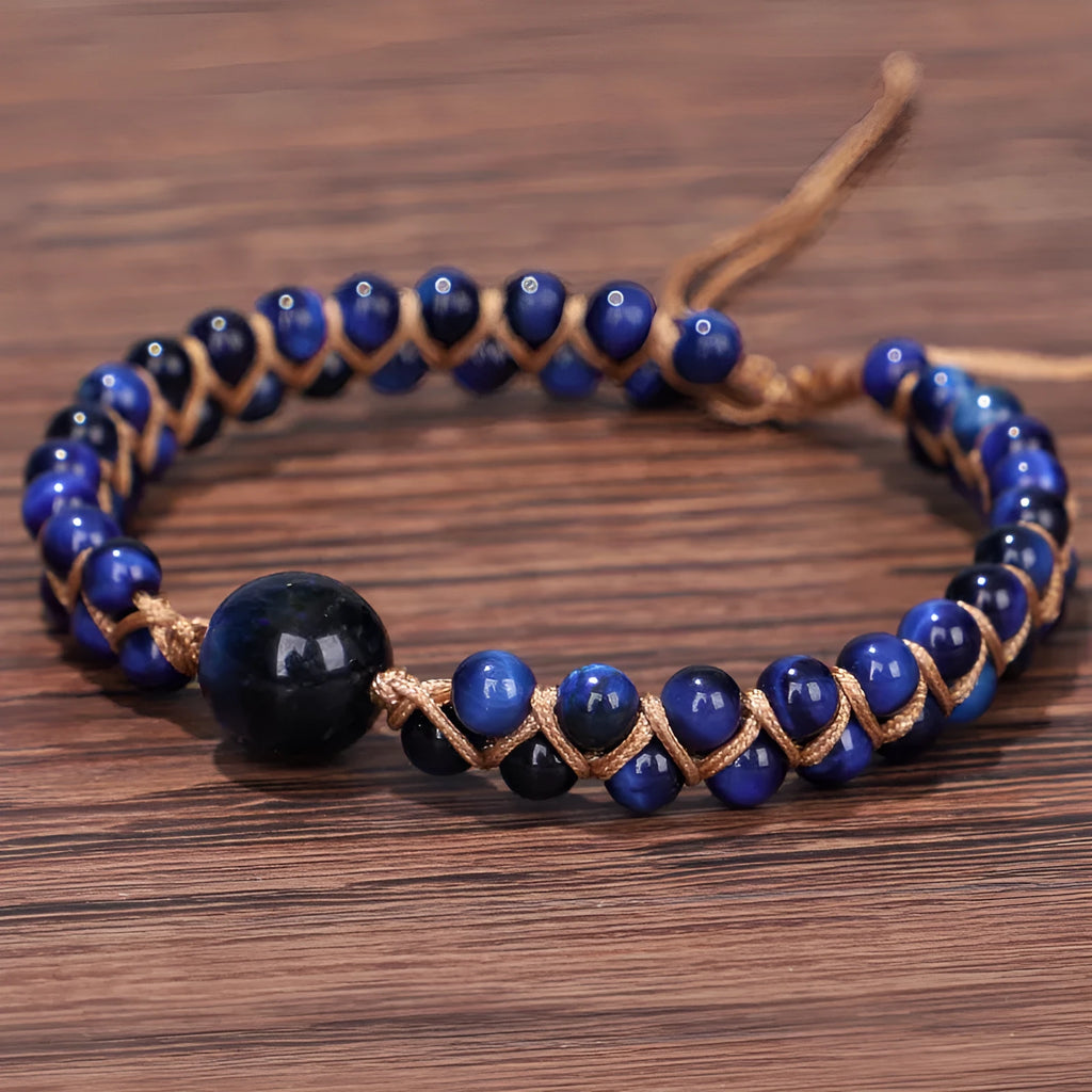 Handwoven geometric pull bracelet made from blue Tigereye stone on a wrist.
