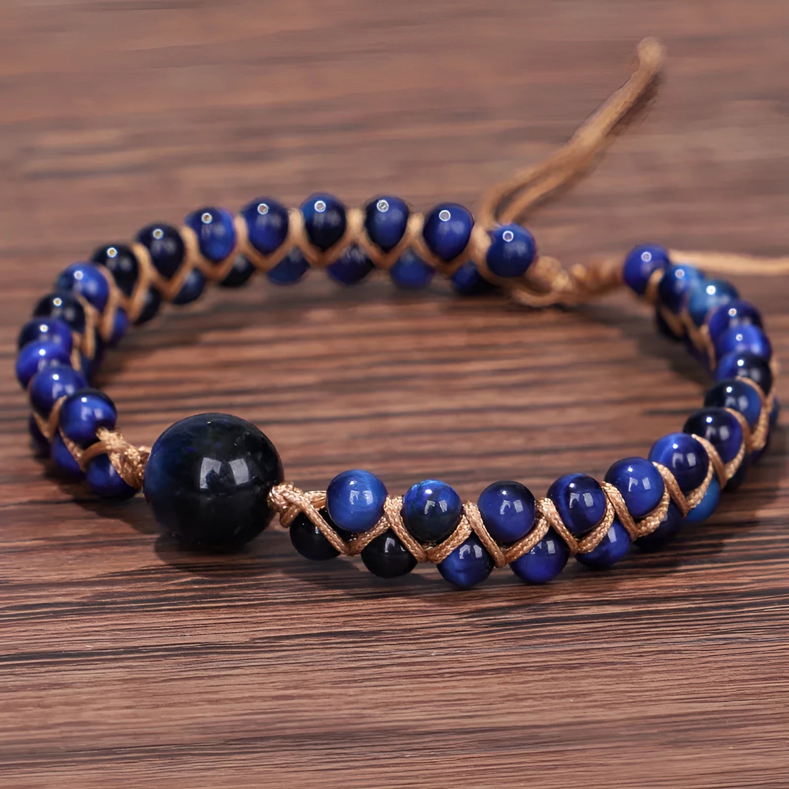 Handwoven geometric pull bracelet made from blue Tigereye stone on a wrist.