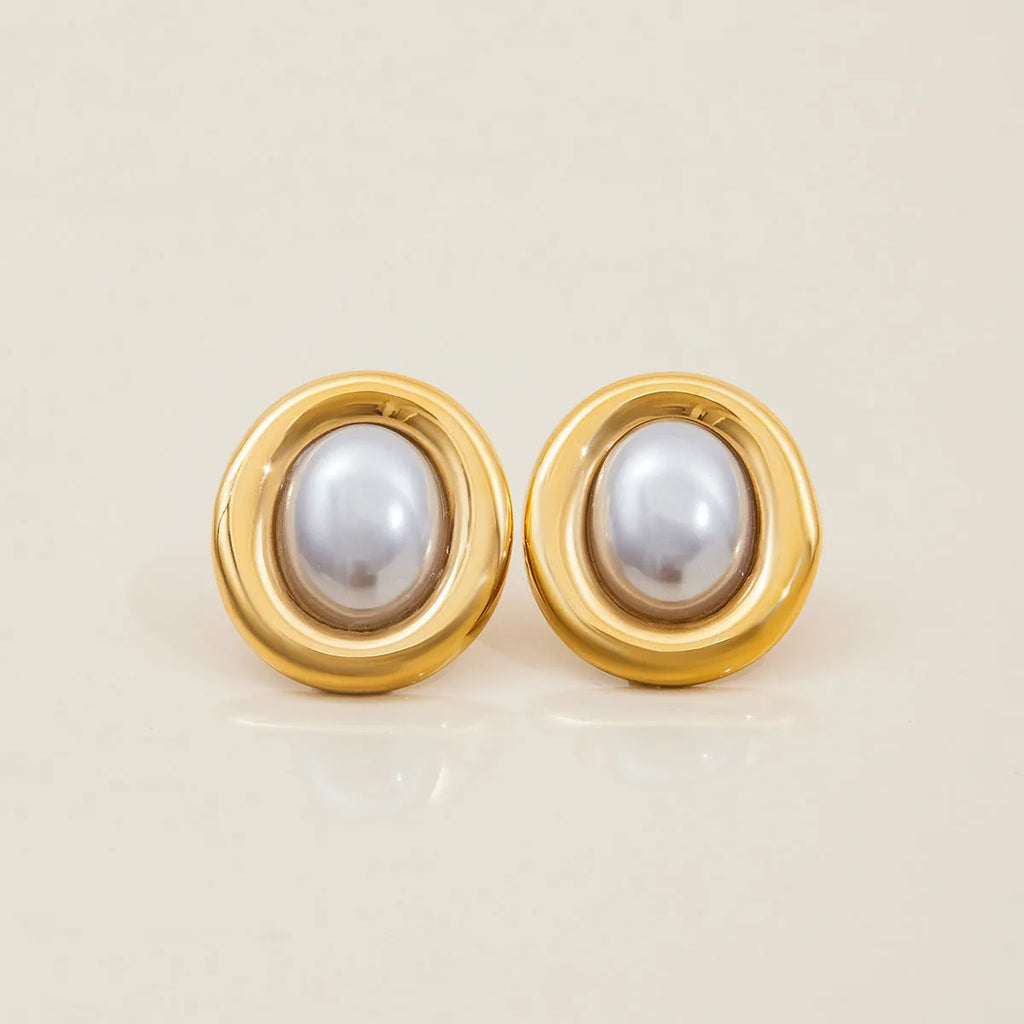 Small gold-tone stainless steel stud earrings with a white pearl accent on a grey background.