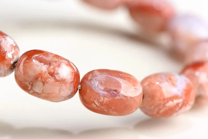 Natural cherry agate bracelet with barrel-shaped beads showing geometric design and Ruyi patterns