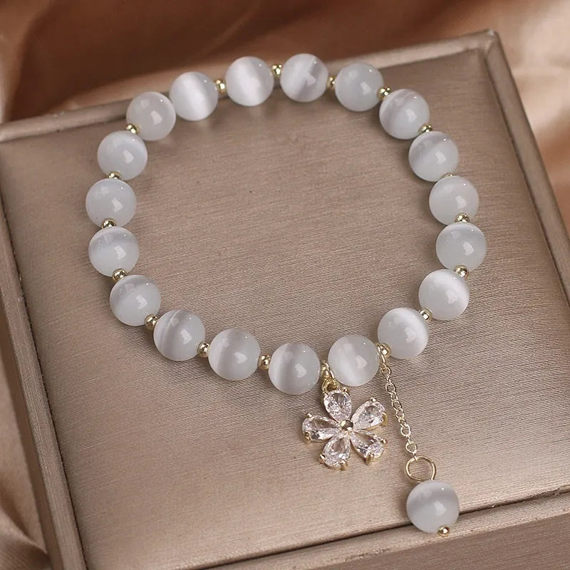 Women's white cat's eye stone bracelet with flower tassel and safety buckle pendant.