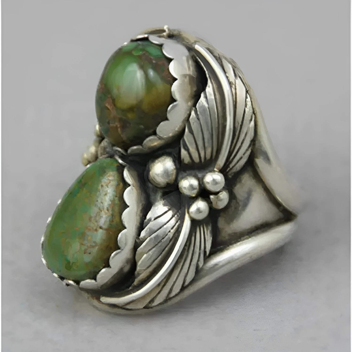 Close-up of a women's geometric turquoise ring with a retro inlaid design on a finger.
