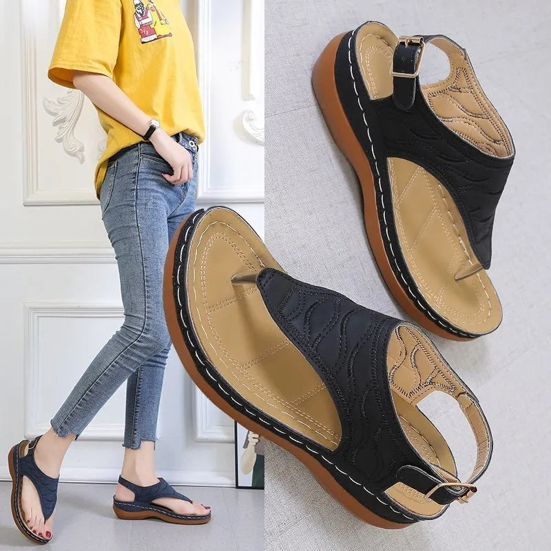 Women's wedge heel flip flop sandals with an adjustable buckle back strap in black.