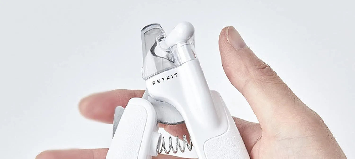 White pet nail clippers with LED light, anti-splash guard, and built-in file on a grey surface