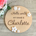 Square wooden newborn name label showing baby birth information and surname on a plywood plaque.