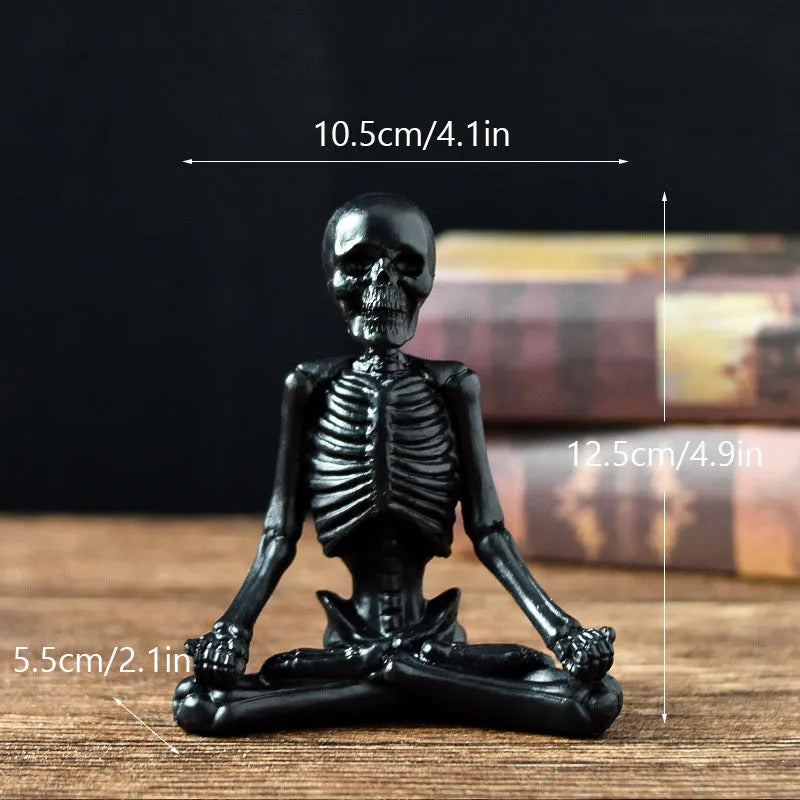 Detailed resin ornament of a yoga pose skeleton skull on a desktop, shown in black and white colour options.