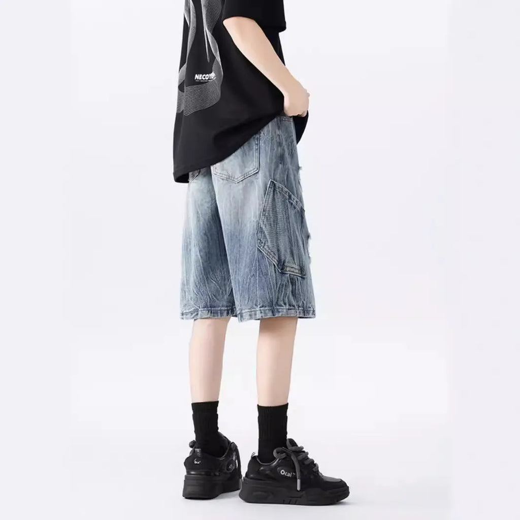 Loose washed blue denim shorts with a ripped knee detail on a mannequin, showing the retro fit.