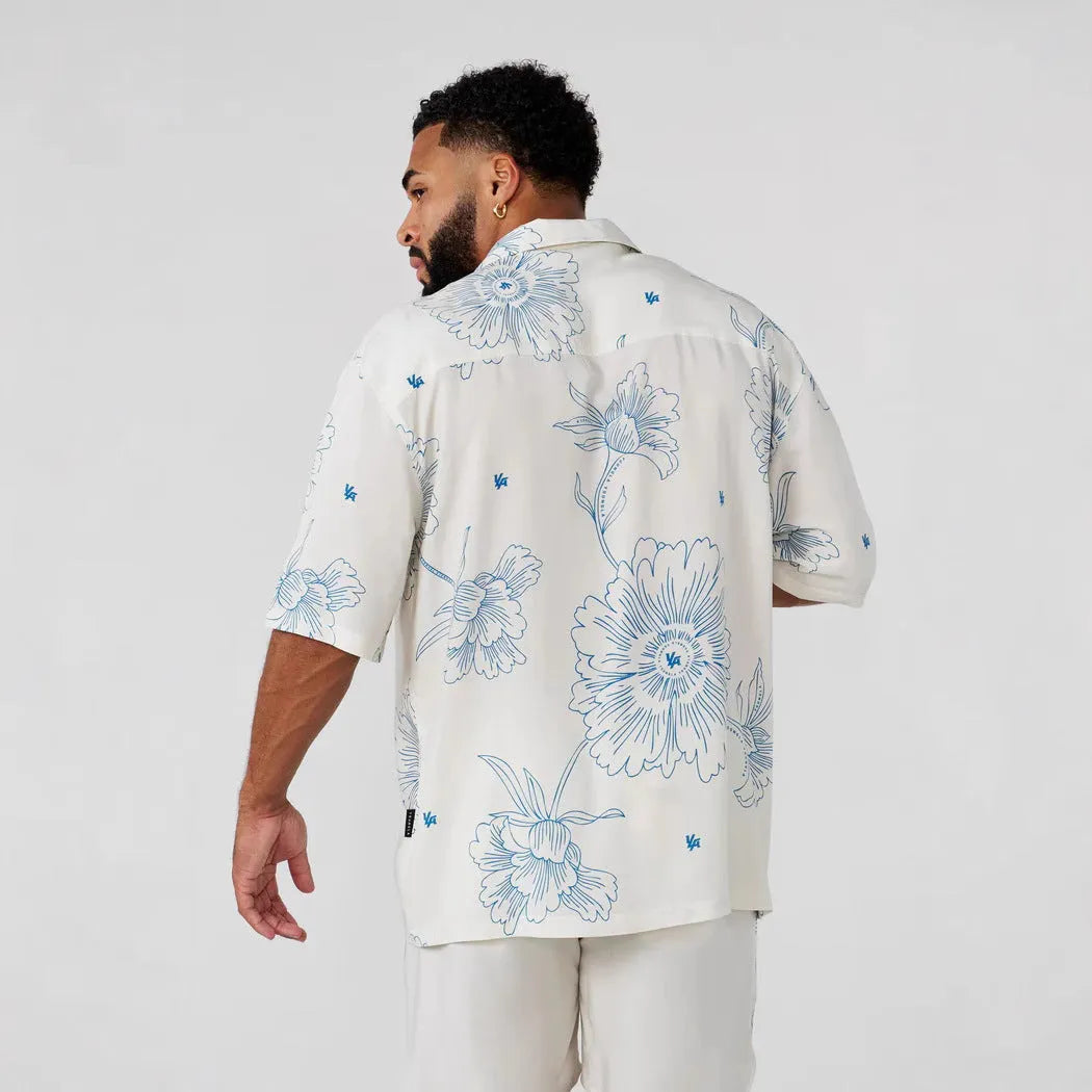 Man wearing a loose-fit, short sleeve floral print top in a neutral colour.