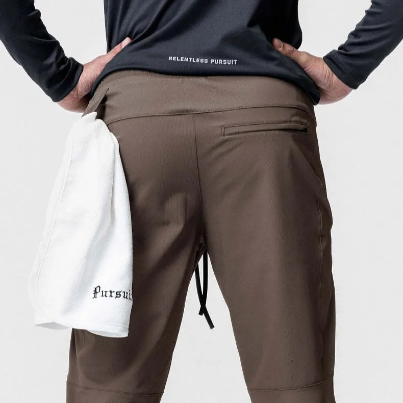 Men's loose grey fitness trousers with ankle ties on a gym floor.