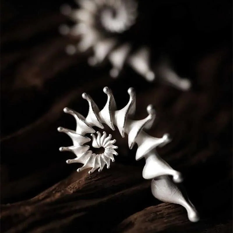 Exaggerated three-dimensional conch shell stud earrings with a matte finish in an irregular abstract design.
