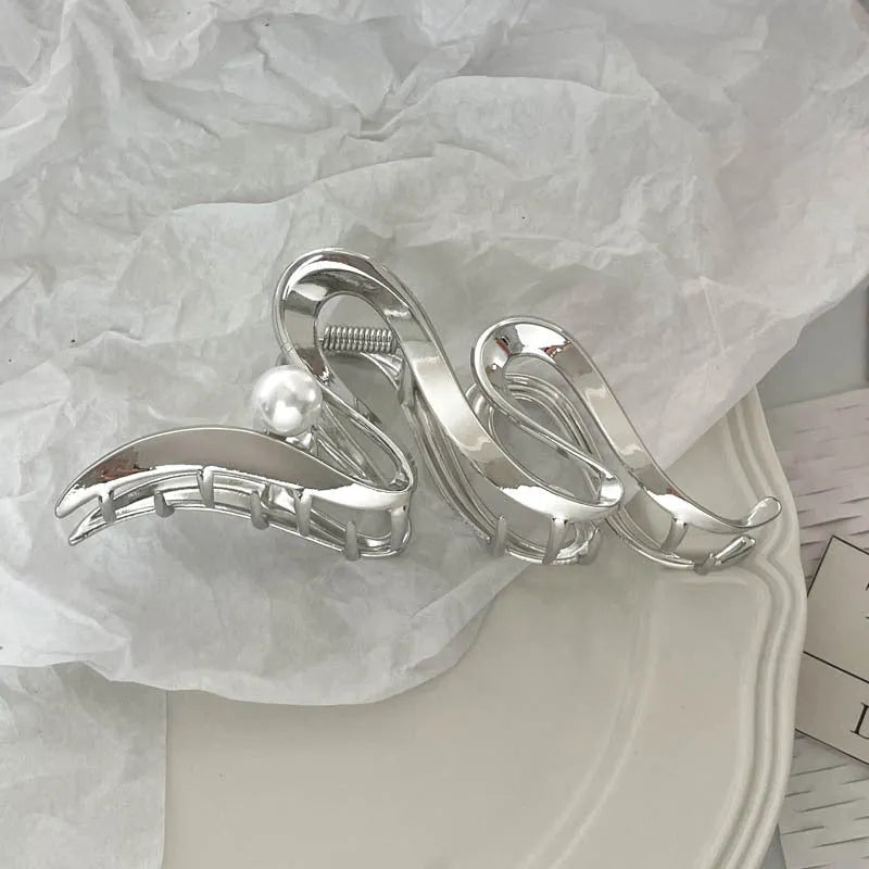 Silver metal hair claw clip assortment showing bows, waves, pearl designs, and geometric shapes from 4cm to 13.5cm