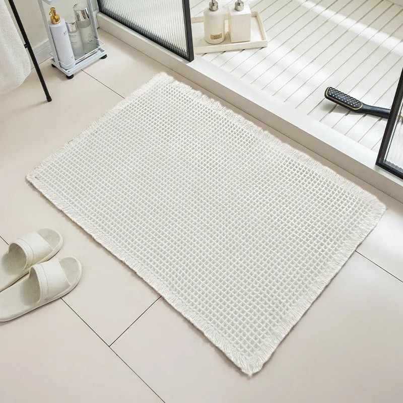 Modern checkered pattern absorbent non-slip bathroom floor mat in a neutral colour on tiled floor.