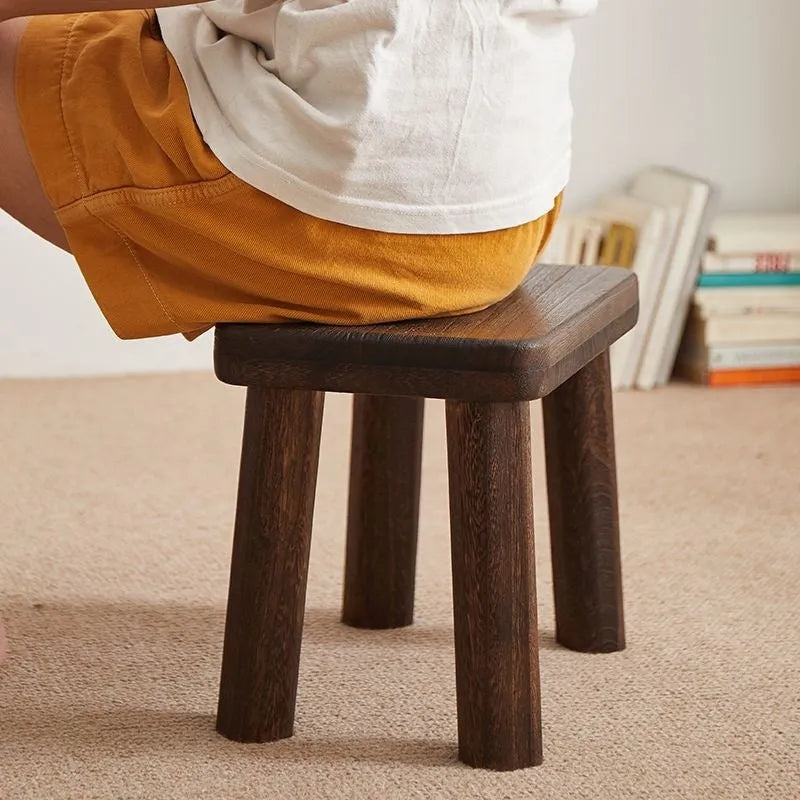 Rustic distressed wooden changing stool with bracket structure for shoe removal.
