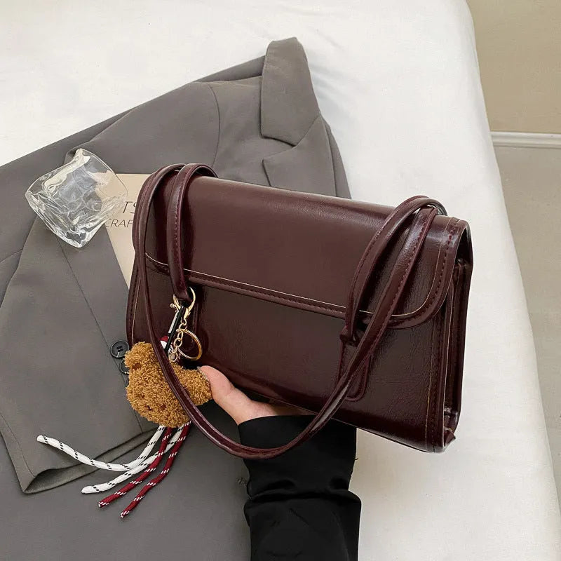 Women's brown PU leather shoulder bag with square shape, double straps, and decorative pendant attachment