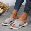 Black wedge platform slippers with a cross strap and open peep-toe design on a white background.