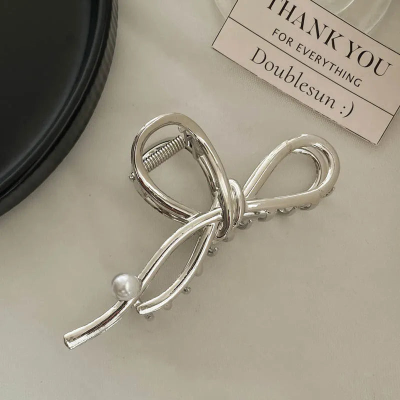 Silver metal hair claw clip assortment showing bows, waves, pearl designs, and geometric shapes from 4cm to 13.5cm