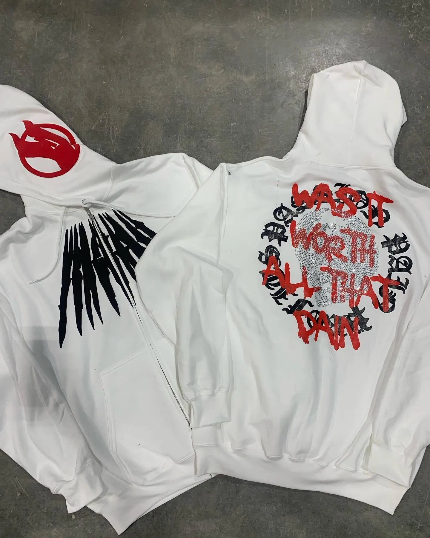 Black loose hooded cardigan sweatshirt with white skull and rhinestone print, long sleeves.
