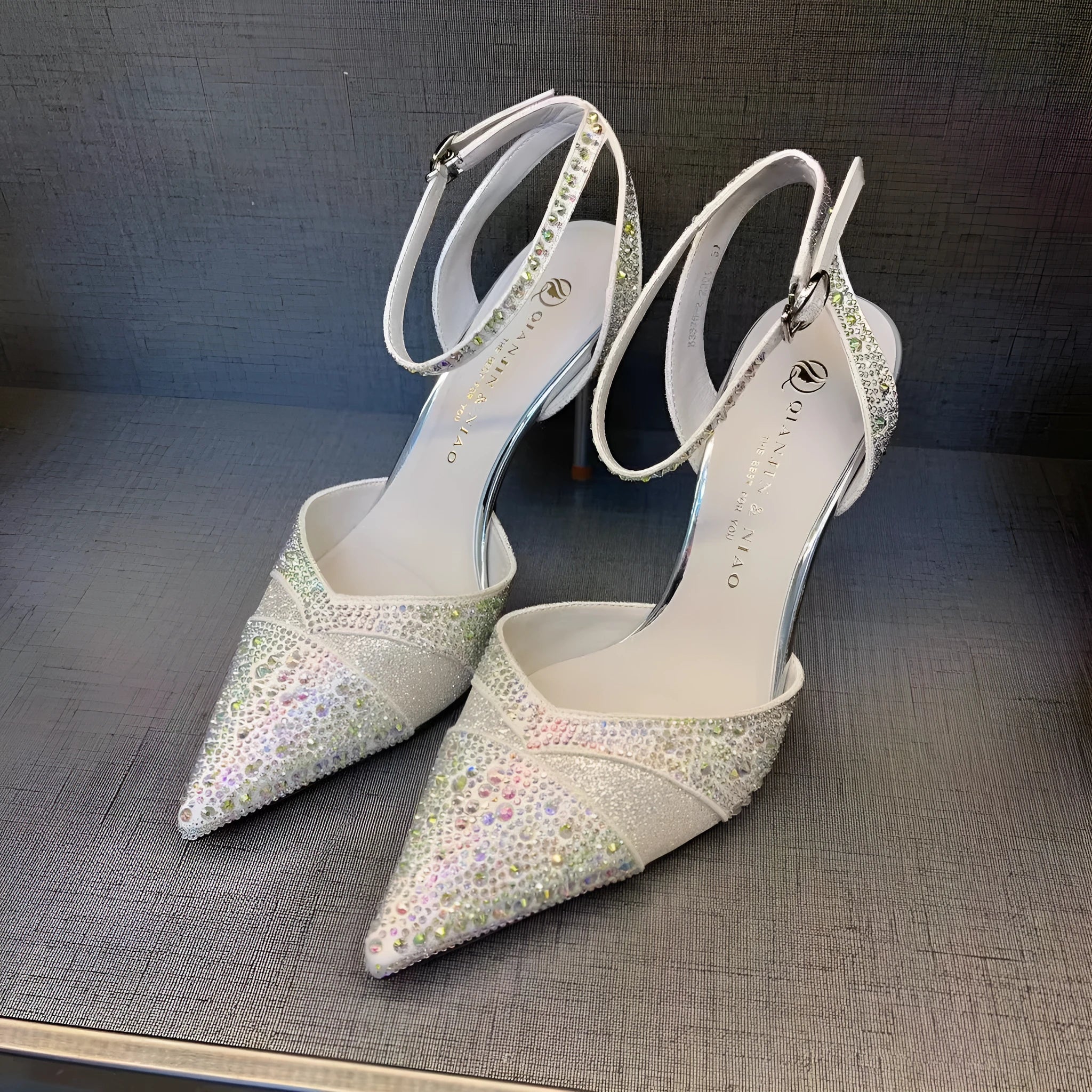 Women's silver hollow stiletto heels with pointed toe and red sole on white background