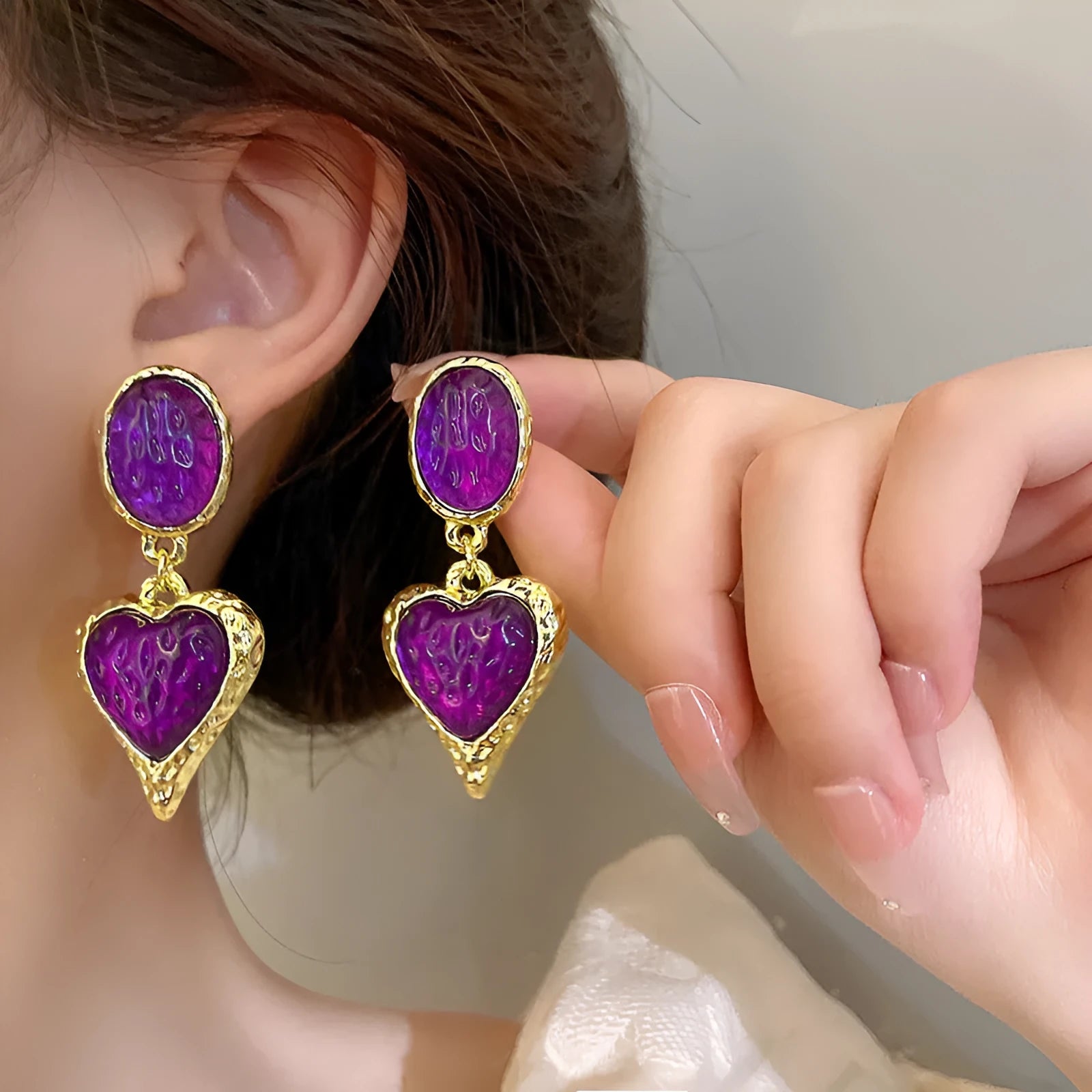 A pair of pleated oval love heart stud earrings in alloy, showing the silver needle post.