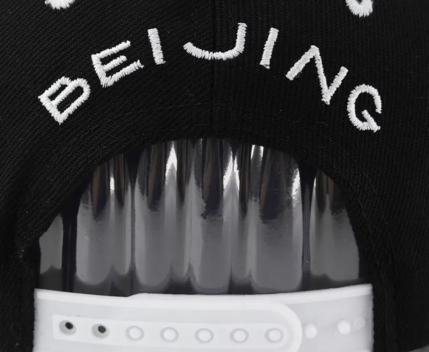 Cotton baseball hat with embroidered letters on a dome crown, shown in black and white.