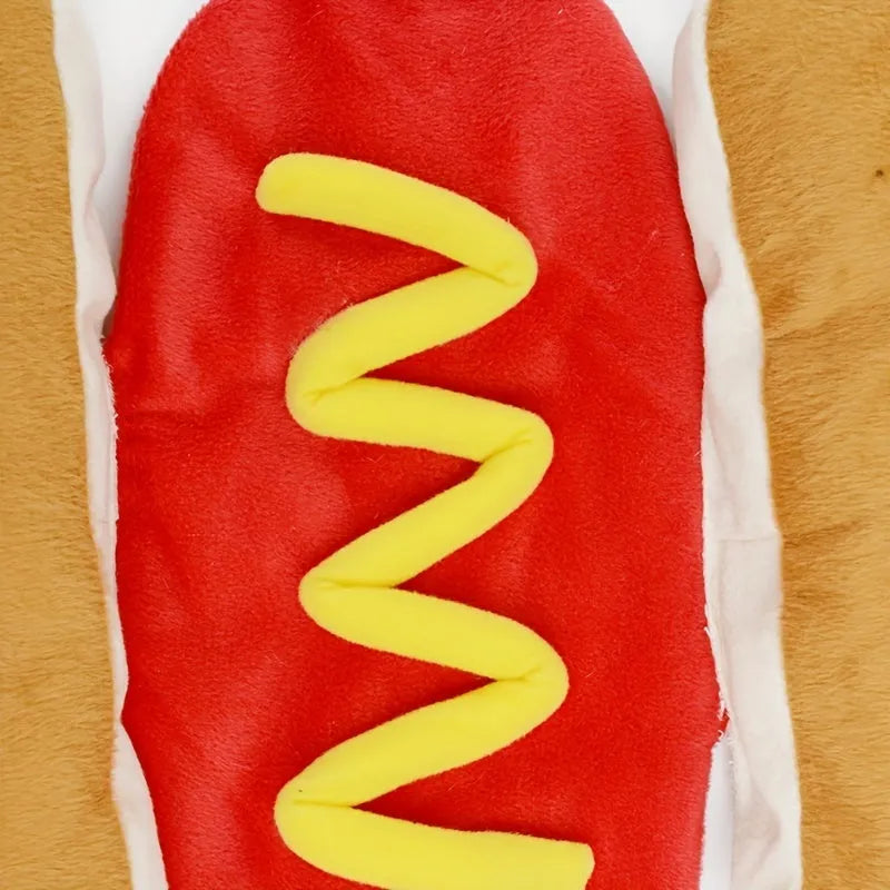 A small dog wearing a plush red and brown hot dog costume suit with mustard detailing.