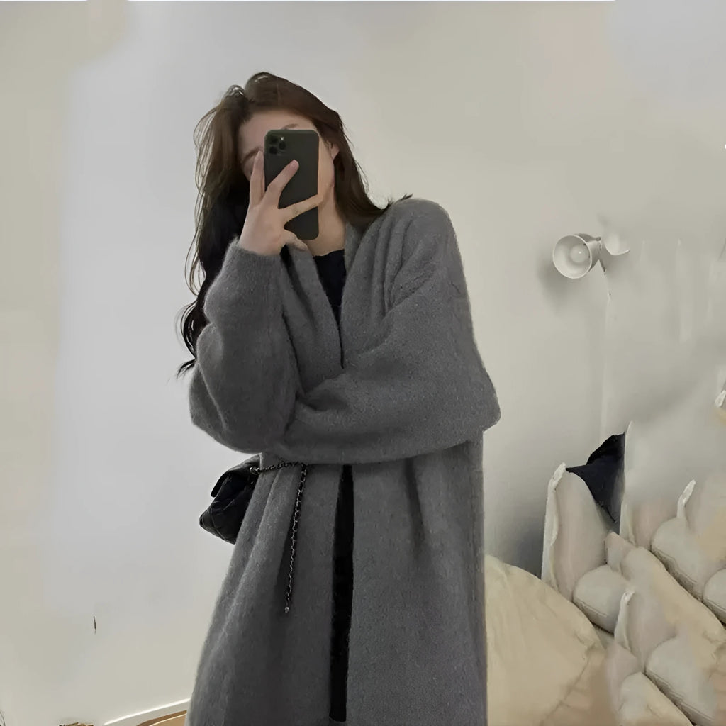 Loose black knitted women's cardigan with a 3D pattern, shown open over a white top.