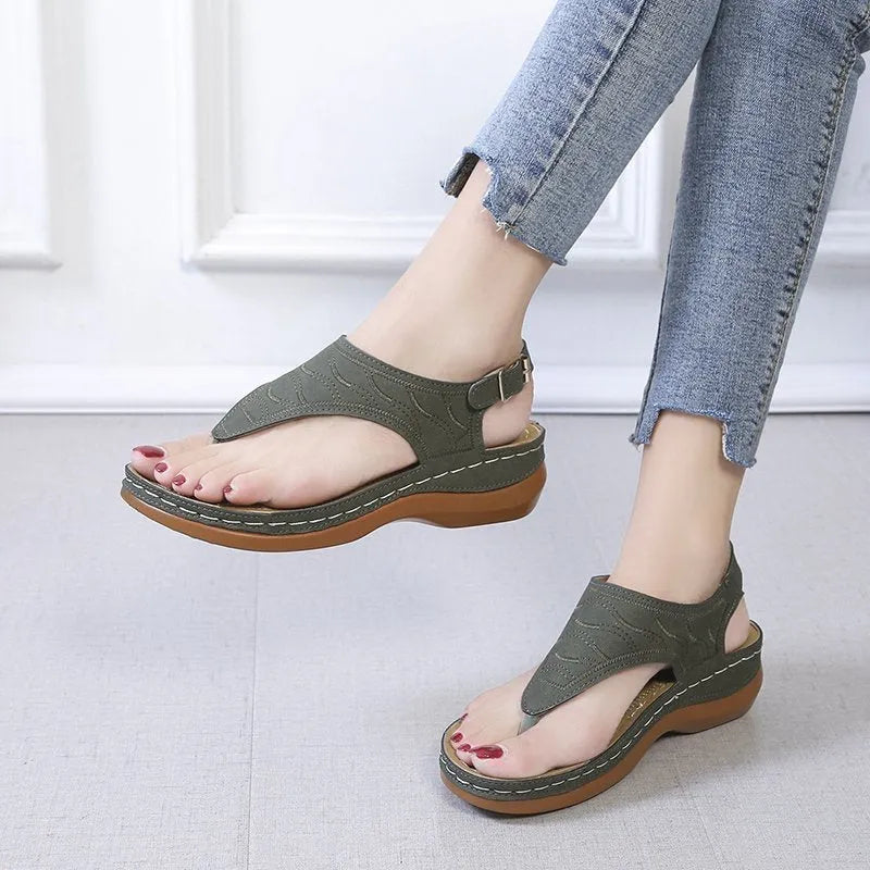 Women's wedge heel flip flop sandals with an adjustable buckle back strap in black.