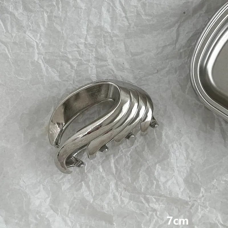 Silver metal hair claw clip assortment showing bows, waves, pearl designs, and geometric shapes from 4cm to 13.5cm