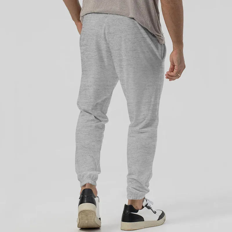 Men's grey loose-fit tapered track sweatpants with a straight leg on a neutral background.